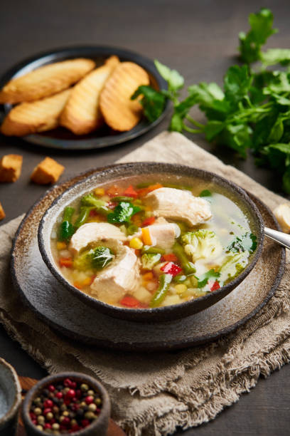 istock Homemade chicken soup with vegetables, broccoli on dark brown background, vertical, side view. 1139614075