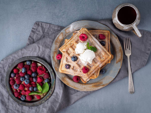 istock Belgian waffles with raspberries, chocolate syrup. Breakfast with tea on dark background, top view 1139614257
