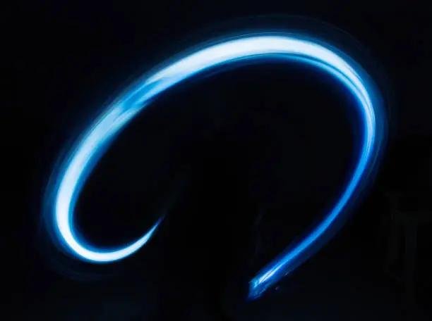 Photo of Glowing shiny curve light trail lines effect in black background.