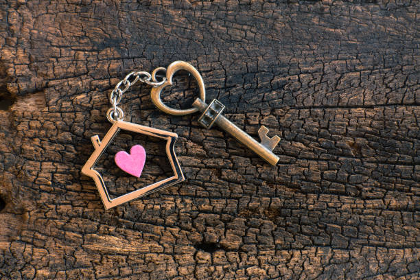 House key in heart shape with home keyring on old wood background decorated with mini heart, home sweet home concept, copy space stock photo