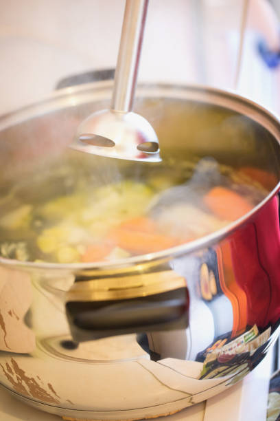 outdoor cooking bean meal, stewed meat and vegetables in big metal kettle with big wooden spoon
