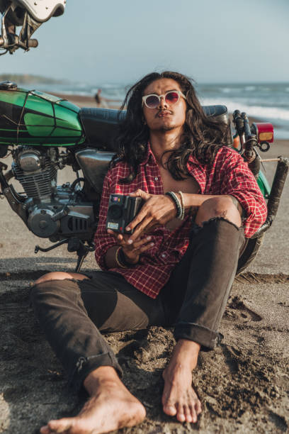 istock Guy with instant camera sitting on the beach 1139628496