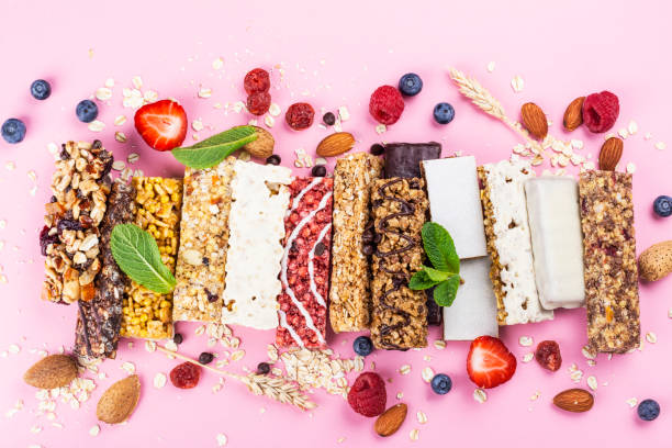 Homemade granola cereal bars Assortment of different granola cereal bars on pink background. Healthy pre or post workout snacks with fruits, nuts and berries. Copy space. Top view snack stock pictures, royalty-free photos & images