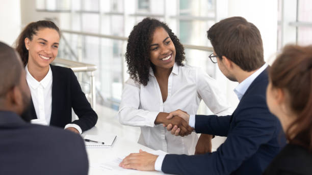 Diverse business partners shaking hands starting collaboration at group negotiations Multiracial businessman businesswoman shake hands starting collaboration at group negotiations, positive people gathered at modern office boardroom, partnership teamwork and business etiquette concept recruitment team stock pictures, royalty-free photos & images
