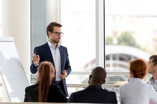 Mid adult teacher explaining lesson to university students in the classroom at university