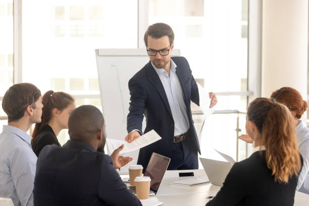 istock Confident coach giving handout to diverse seminar participants 1139630482