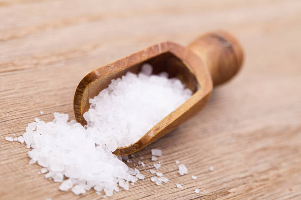 Wooden spoon with salt on wooden board stock photo