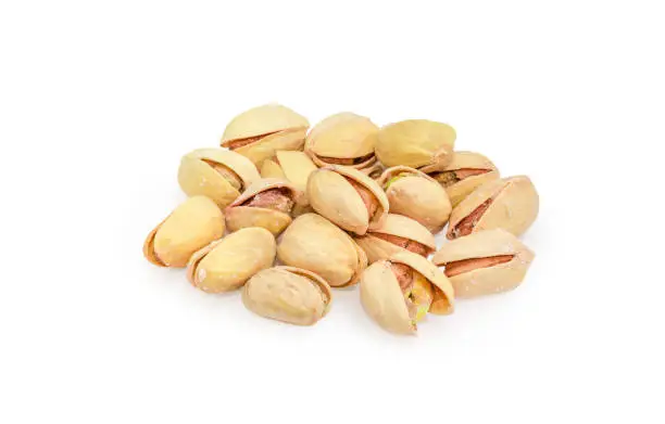 Small pile of the roasted salted pistachio nuts with partly open shells on a white background