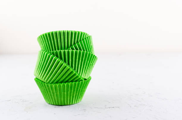 Brightly green colored paper baking cups for cupcakes or muffins on light grey conkrete background, copy space