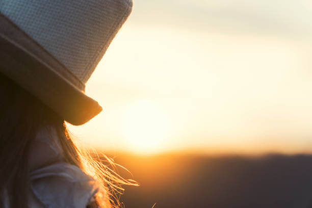 pretty woman enjoying the sunset, solo traveler, fashion girl, one young woman tourist enjoying the sunrise light, portrait, back lit, travel, exploration, adventure, tourism, outdoors, springtime, - back lit women one person spring imagens e fotografias de stock