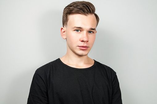 White young guy dressed in a black t-shirt on white background looking