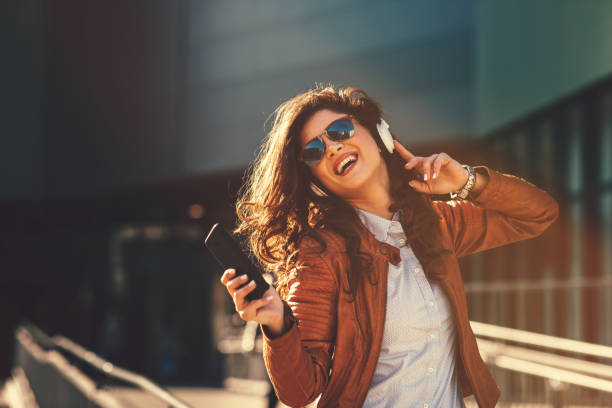 Young modern woman enjoys music on the street via headphones stock photo