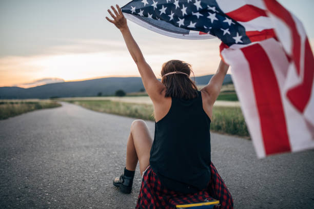 istock Lady sitting on skateboard and holding US flag 1139656529