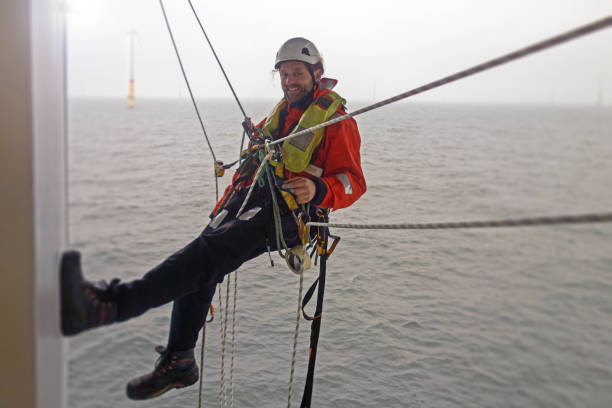 sourire manuel de haut travailleur offshore de rappel sur la plate-forme offshore avec des ropers - working windmill photos et images de collection