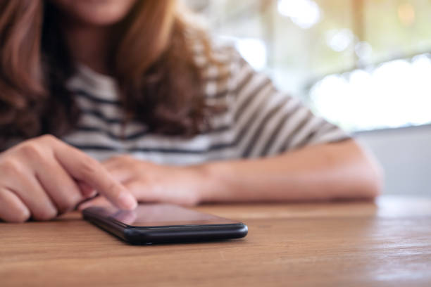 istock A beautiful woman using and touching a smart phone screen on wooden table 1139657864