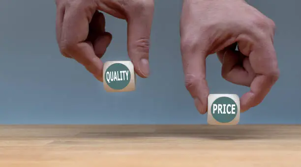Photo of Symbol for choosing quality instead of a cheap price. Two Hands hold two dice with the words 