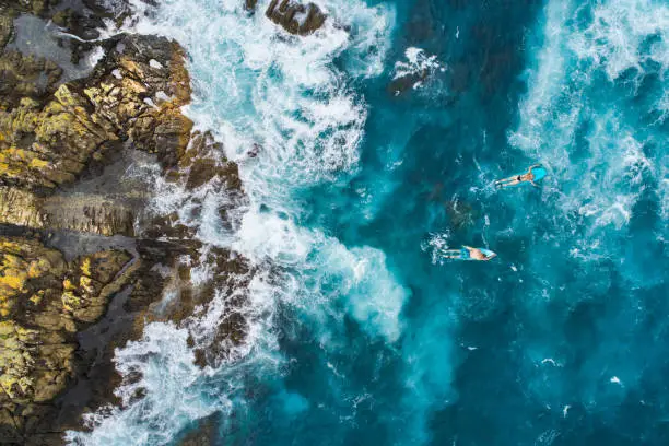 Photo of Aerial view of surfers on their surfboards.