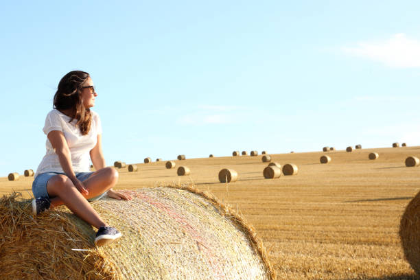 istock Young Lady sitting on haybale awaiting sunset 1139668789