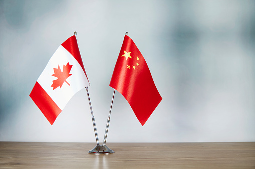 Chinese and Canadian flag standing on the table with defocused background