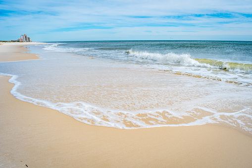 A beautiful sea whitecap waves roll onto the sandy beach of Pensacola