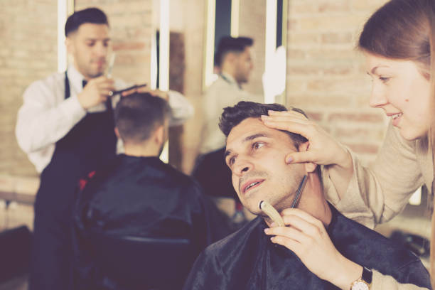 istock Woman barber shaving client with straight razor 1139682866