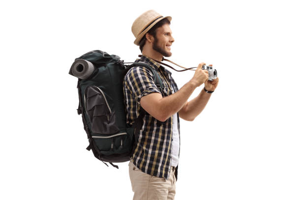 Young male tourist with a backpack and a camera isolated on white background