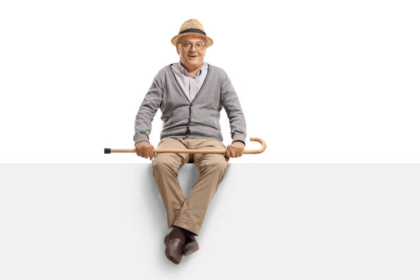 istock Senior man sitting on a blank billboard panel and holding a walk 1139684723