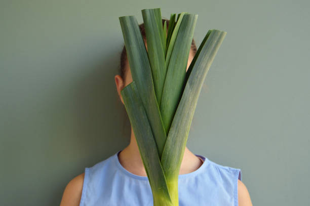 Girl holding leek in front of face