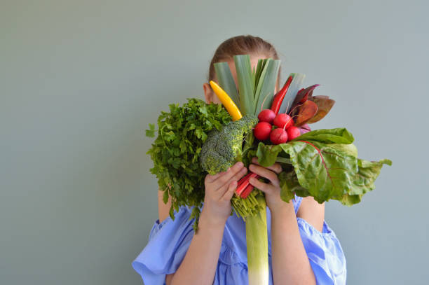 chica sosteniendo ramo de verduras - comida vegetariana fotografías e imágenes de stock