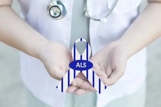 Photo of Doctor in white uniform with clinical stethoscope hold stripe blue and white ribbon awareness with text Stop ALS in hand for ALS or Amyotrophic Lateral Sclerosis Awareness