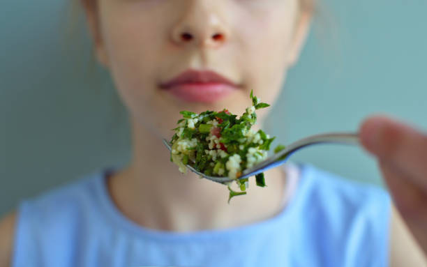 Crop close up shot of girl eating salad Crop close up shot of girl eating salad vegetarianism stock pictures, royalty-free photos & images