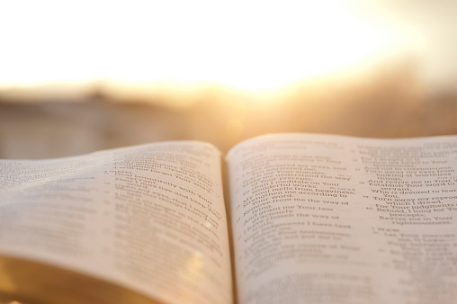 Biblia abierta con brillante puesta de sol en el fondo. photo