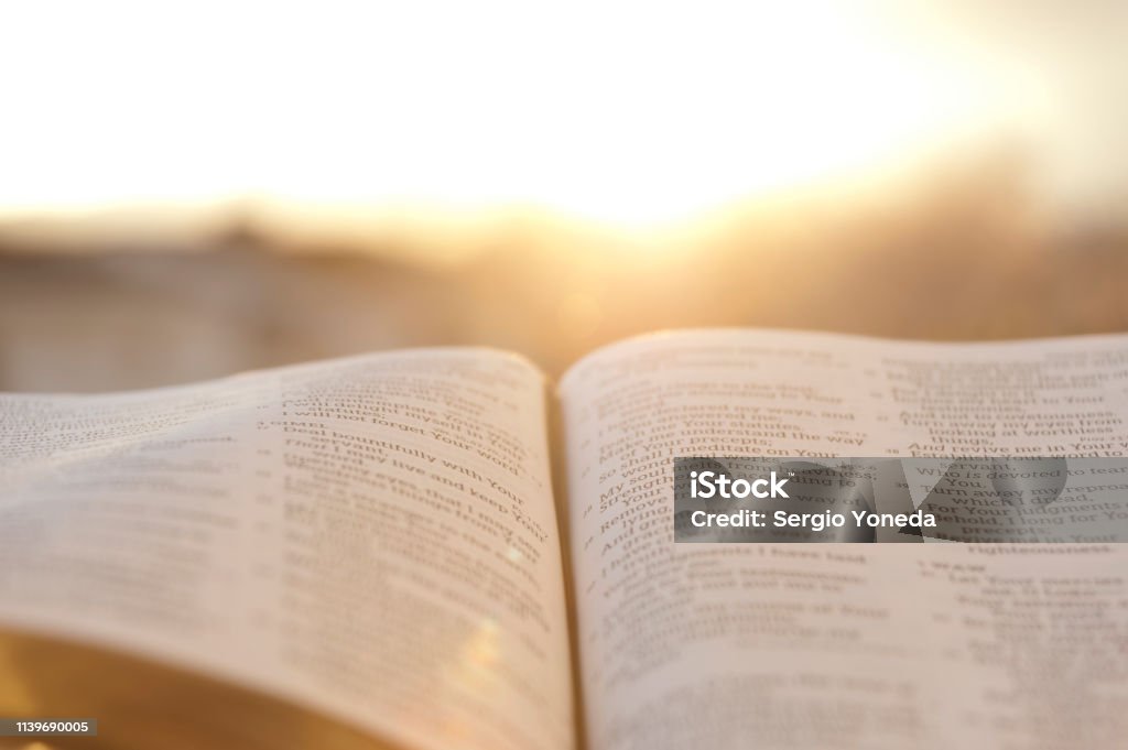 Open Bible with bright sunset in the background. OpenBible with bright sunset in the background. Close-up. Horizontal shot. Bible Stock Photo