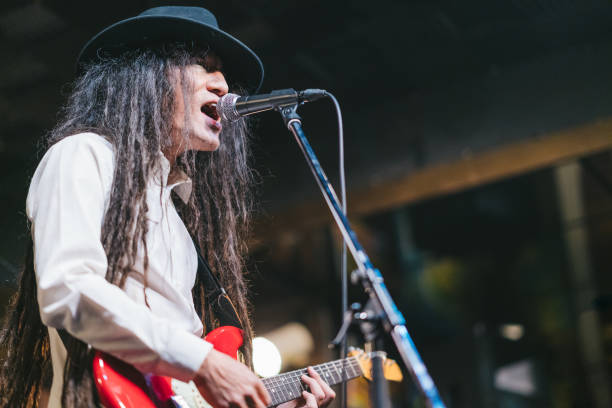 istock Male musician with dreadlocks playing guitar and singing on stage 1139703349