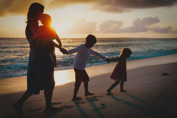 istock mother and kids walking on beach at sunset 1139704181