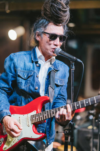 istock Male musician with dreadlocks playing guitar and singing on stage 1139704689