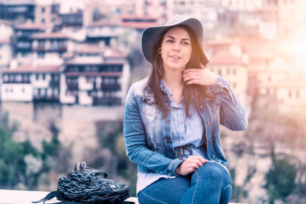 pretty hispanic girl smiling, solo traveler at sunset, one young woman tourist enjoying the sunset light, portrait, back lit, travel, exploration, adventure, tourism, outdoors, generation z, springtime, city break - back lit women one person spring imagens e fotografias de stock