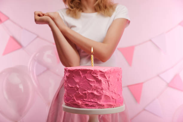 selective focus of cake stand with tasty pink birthday cake and burning candle near woman selective focus of cake stand with tasty pink birthday cake and burning candle near woman woman birthday cake stock pictures, royalty-free photos & images