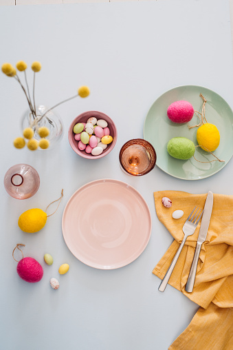 Easter table setting with cutlery plates dinnerware easter egg\nPastel colored photo taken from above overhead