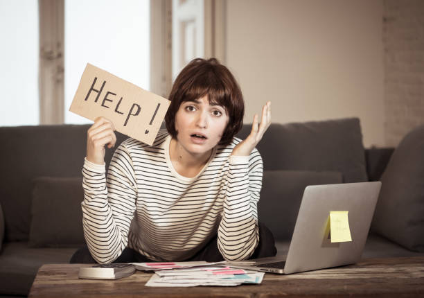 Unemployed woman in front of her laptop holding a card that says help!