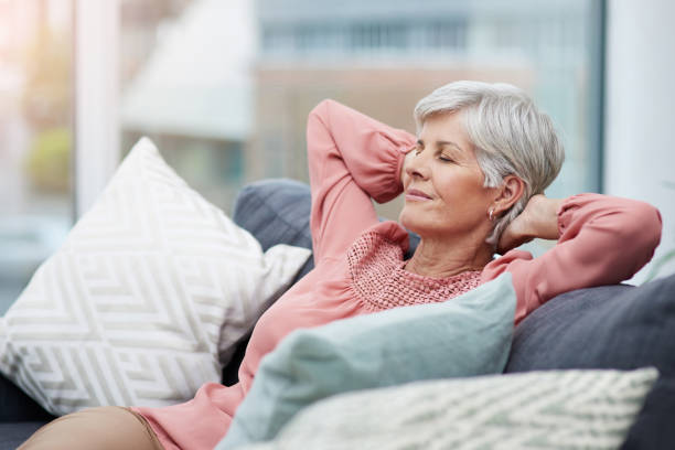 Time to kick back and relax Shot of cheerful mature woman laid back and relaxing on her sofa at home eyes closed photos stock pictures, royalty-free photos & images