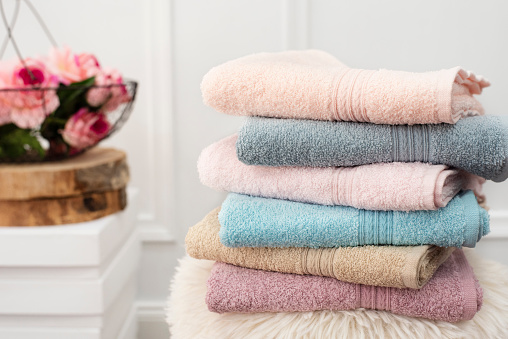 Pila de toallas limpias de colores suaves. Flores en el fondo photo