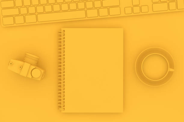 istock Top view of notebook with camera and keyboard on yellow background 1139717890