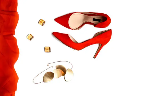 Photo of Top view to party outfit composition: red shoes, accessories, jewelry on white background, isolated.