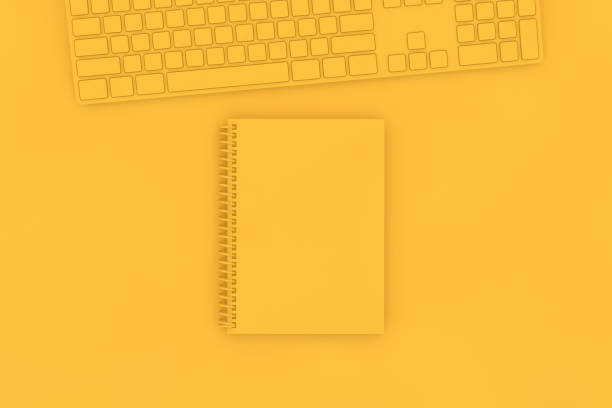 istock Top view of notebook with pc keyboard on yellow background 1139719546