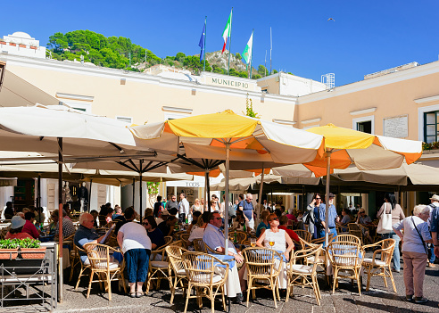 Capri, Italy - October 3, 2017: People in Street cafe and restaurant with table and chair, Capri Island, Naples, Italy. Cityscape with tourists at Cafeteria, Italian coast. Anacapri in Amalfi