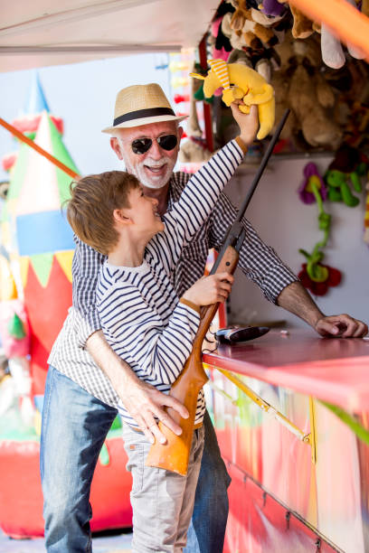istock Little boy with grandfather having fun at amusement park 1139720937