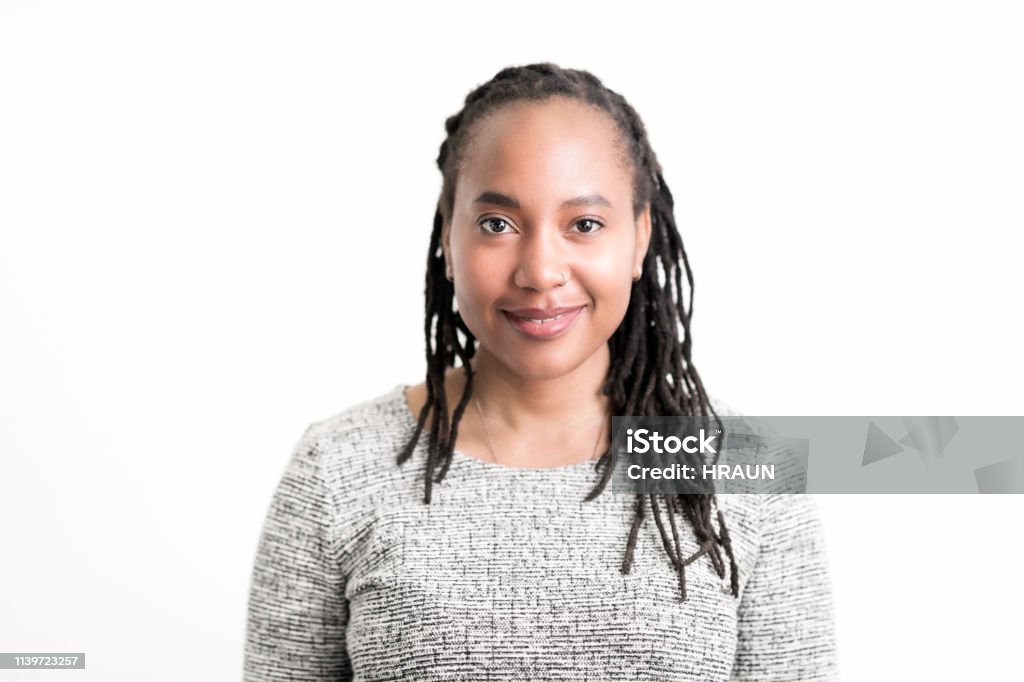 African American woman smiling on white background Portrait of young woman smiling. Close-up of beautiful female is with long dreadlocks. She is wearing casuals against white background. White Background Stock Photo
