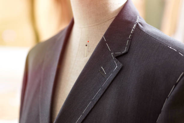 Tailored suit jacket with alterations marked with basting stitch on a mannequin at bespoke tailor's workshop.