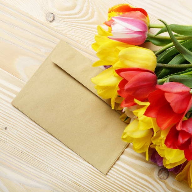 istock Colorful tulips and blank envelope on natural wooden background with space for text 1139726475